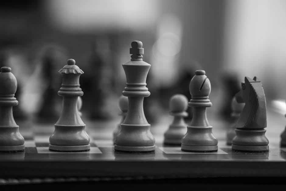 Black and white close-up of chess pieces on a board, highlighting strategic gameplay.